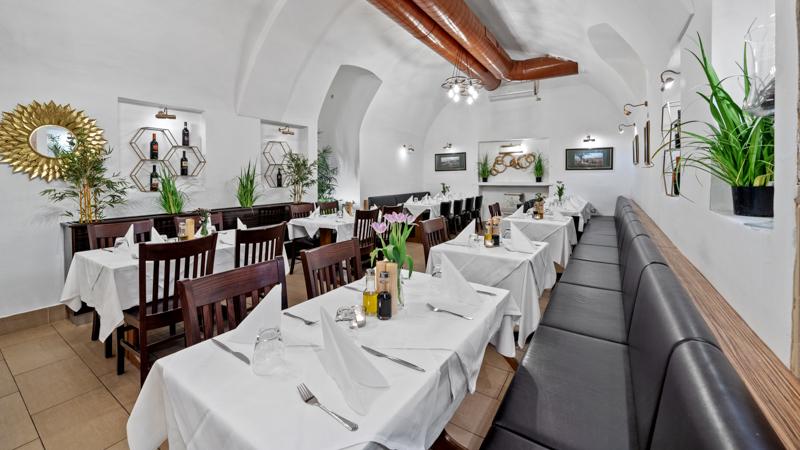 Gewölbekeller des Volare in Wien — weiße Tischwäsche, Weinregale, Lederbank